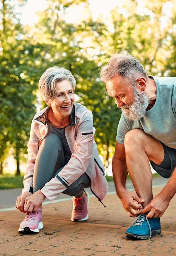 an older man and woman crouching on the ground with their hands on their knees