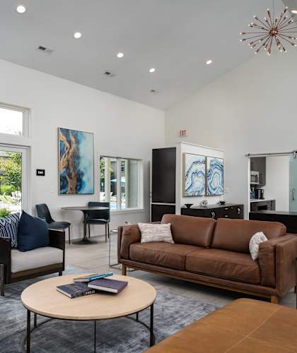A living room with a brown couch, a coffee table, and a large window.