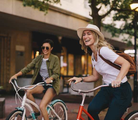 two women riding bicycles down the street on bikes