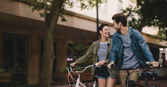 a man and woman walking their bikes down the street
