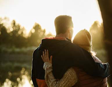 A couple is hugging each other in a sunny outdoor setting.