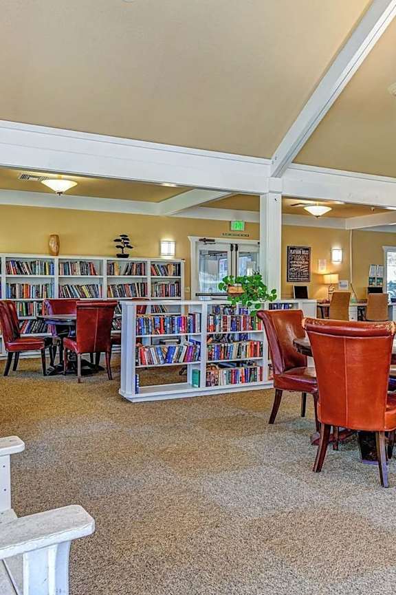 A library with red chairs and bookshelves filled with books.