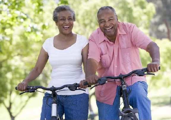 An older couple riding bikes in a park.