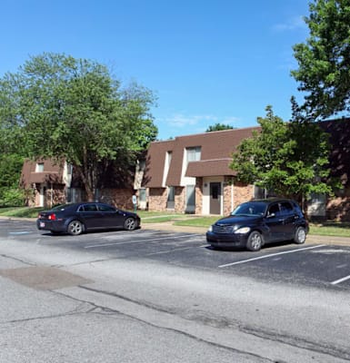 Two cars are parked in a parking lot in front of a building.