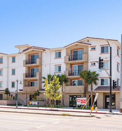 an apartment building on the corner of a street with a blue sky in the background
