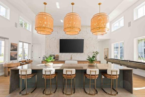 A kitchen with a bar area and a television mounted on the wall.at Verity Luxury Apartments, Vero Beach, FL 32960