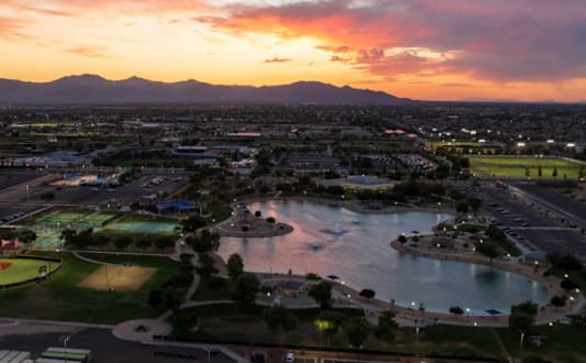 A beautiful sunset view of a city with a lake and mountains in the distance.