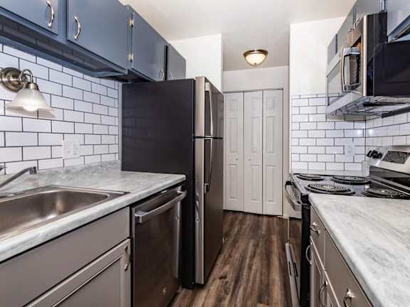 A kitchen with a black fridge and a white door.