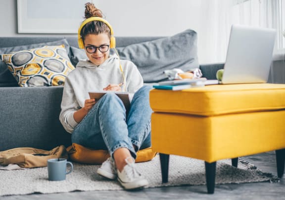 a woman sitting on the floor with a laptop on her couch