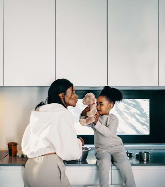 a mom with her daughter and dog sitting in the kitchen at The Farriers Apartments, Milton Keynes, MK8 1LS