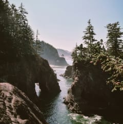 a view of a body of water between rocks and trees