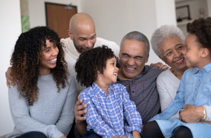 A family of five sitting closely together on a couch.