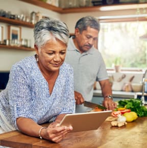 a man and woman in a kitchen looking at a tablet