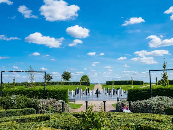 A park with a statue and a bench in the middle of a path at The Woodlands Apartments, Milton Keynes