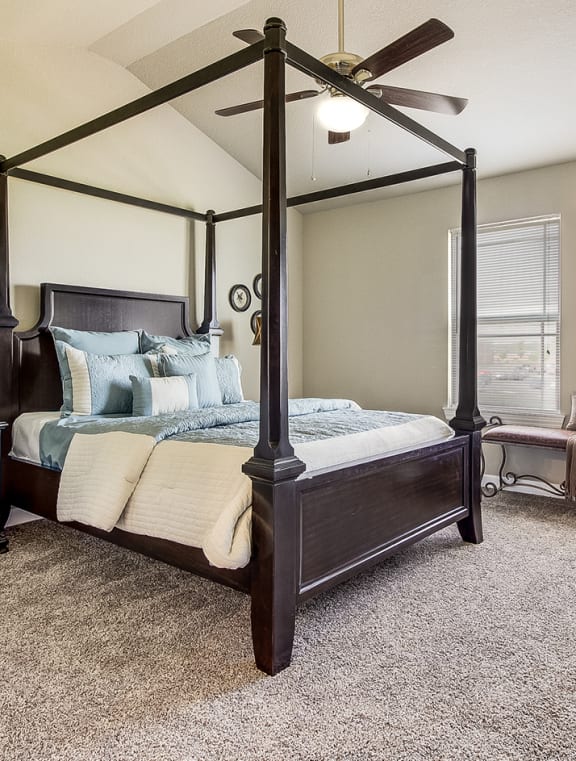 the master bedroom has a canopy bed and a ceiling fan