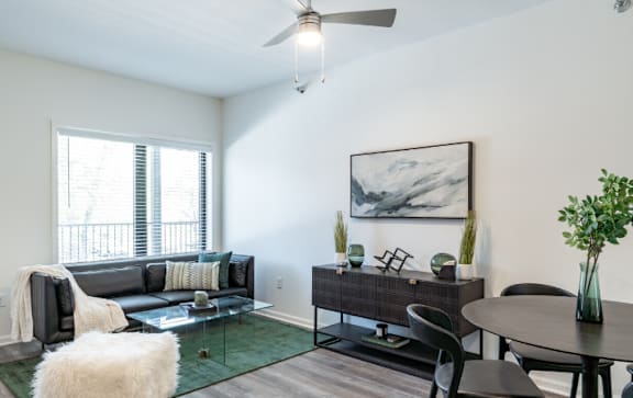 A living room with a couch, chairs, and a painting on the wall.