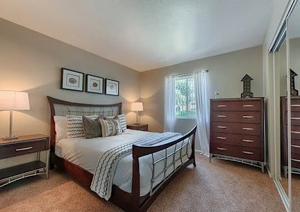 A bedroom with a large bed, two lamps, and a wooden dresser. at Sycamore Square  Apartments, Arizona, 85202