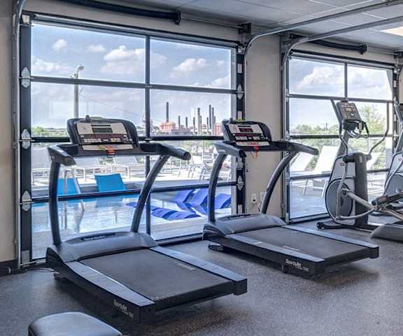 a gym with cardio equipment and a view of a cruise ship