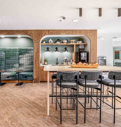 a bar with stools and a counter with chairs in a room with a kitchen