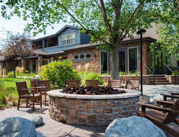 A backyard with a fire pit and chairs.