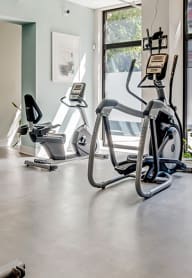 a gym with cardio equipment and a large window at Mercer Commons Apartments