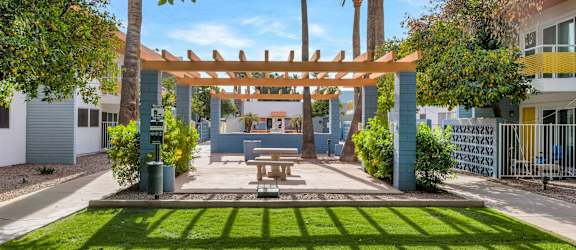 A sunny day at a park with a picnic table and a wooden pergola at The Phoenix Apartments on 6th Avenue, Phoenix