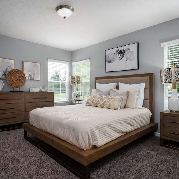 A bedroom with a large bed, a dresser, and a window with blinds.
