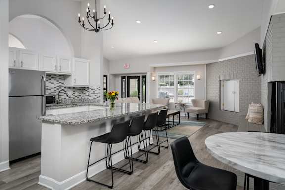 a kitchen with a large island with a breakfast bar and a living room in the background