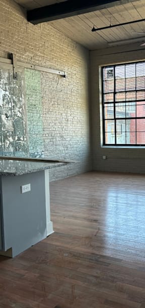 A room with a brick wall and wooden floors.