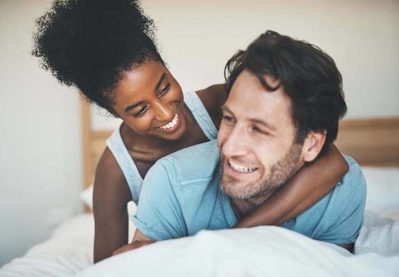 a man and a woman laughing on a bed