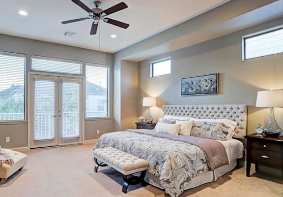 A bedroom with a large bed and a ceiling fan.
