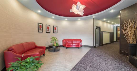 A red couch and a table with a vase on it are in a room with a red ceiling.