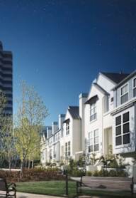 A park with benches and trees in front of apartment buildings.