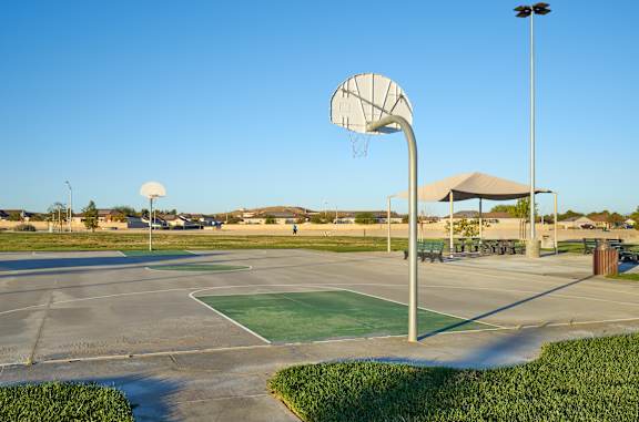 A basketball court with a hoop and a pole.