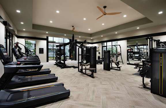 a gym with weights and cardio equipment on the floor and a wall of windows