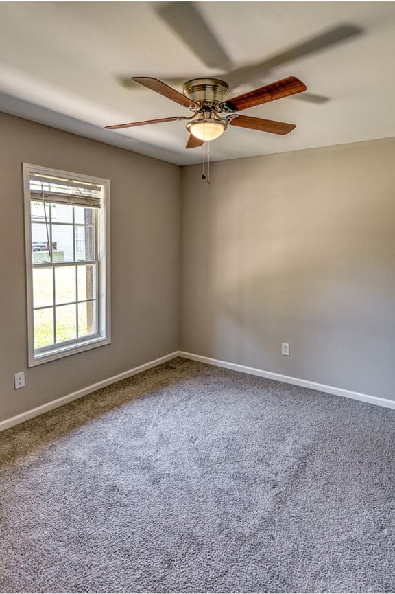 an empty living room with a ceiling fan and a window at Ashford Place Apartments, Kannapolis, NC 28081