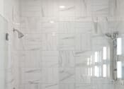 Thumbnail 3 of 51 - A white tiled shower with a white counter top.