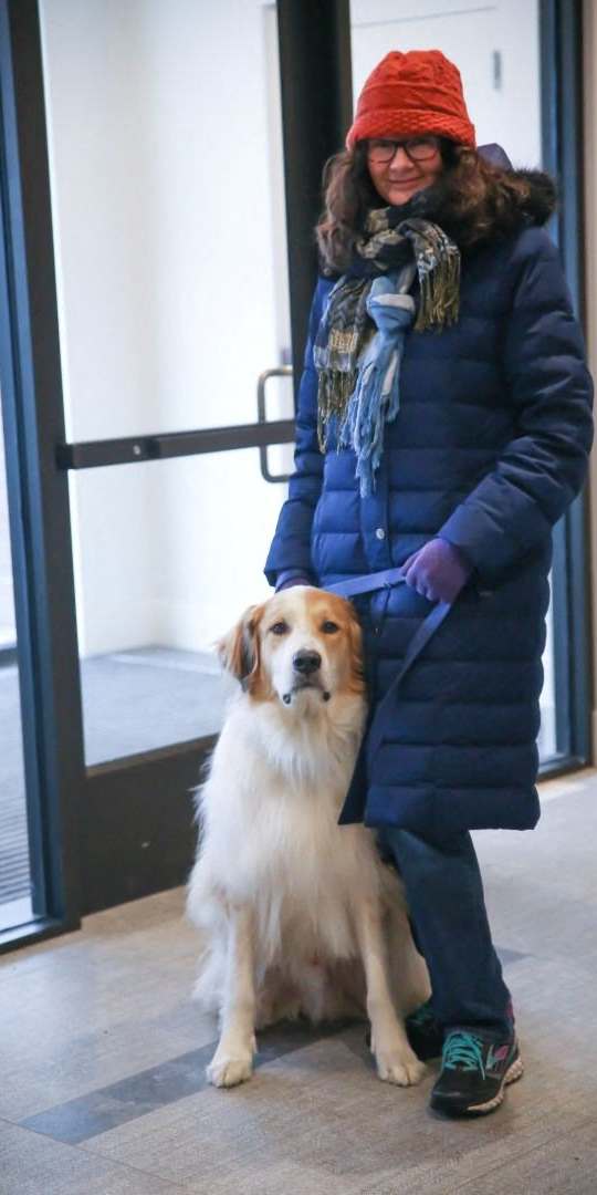 A woman in a blue coat and red hat is standing with her dog. at The M on Hennepin, Minneapolis, MN