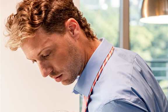 a man in a blue shirt and tie is making a salad