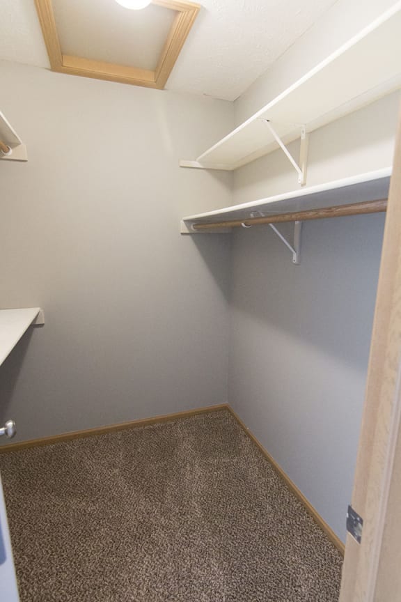 Walk in closet with storage shelves and hanging rods at Cascade Pines