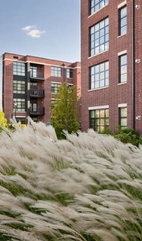 a fountain of grass in front of a brick building at The Sheffield Englewood, Englewood, NJ