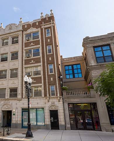 A tall building with many windows is in the middle of a street.
