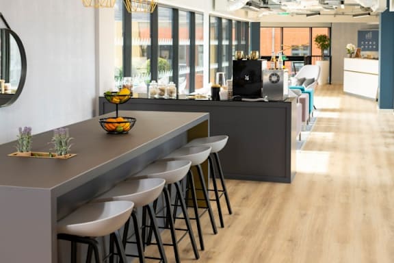 a kitchen with a long counter and chairs in front of a bar at The Trilogy Apartments, Manchester, M15 4RU