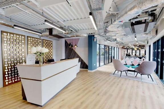 A reception area with a white reception desk and a wooden floor. at The Trilogy Apartments, Manchester, M15 4RU