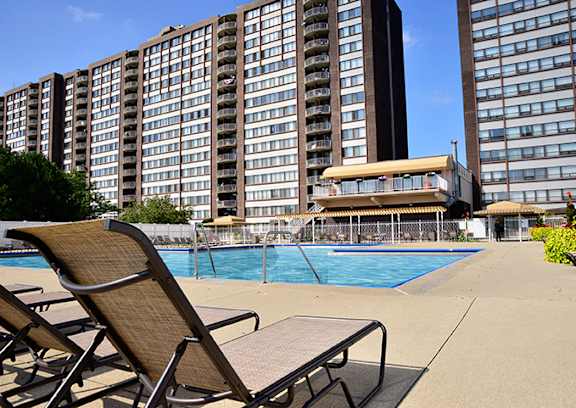 A pool area with chairs and a building in the background.