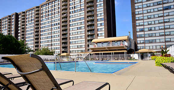 A pool area with chairs and a building in the background.