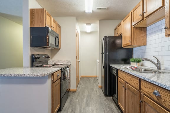 Kitchen with hardwood-style flooring and subway tile backsplash at Williamsburg Park Apartments in Lincoln NE