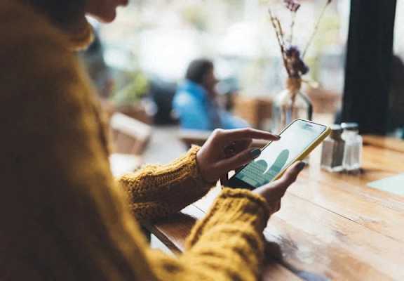 A person in a yellow sweater is using a tablet.