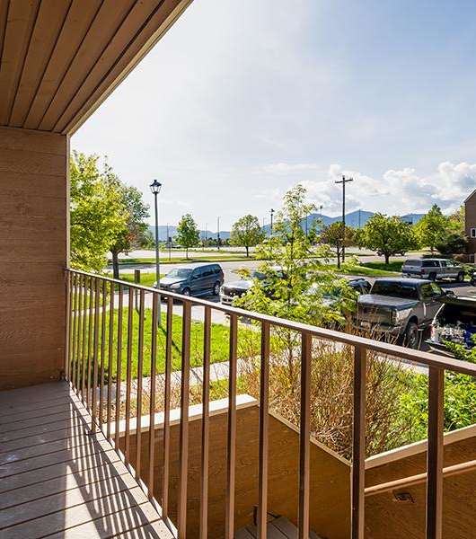 A balcony with a view of a parking lot and houses.