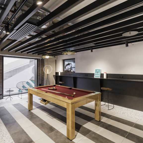 A pool table is in the middle of a room with a black and white checkered floor at Beton Apartments, Wembley, HA9 0SL